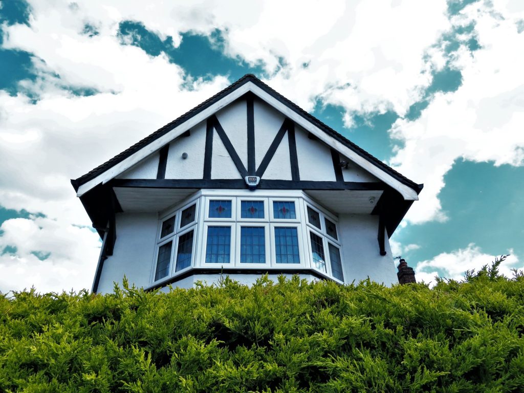 Tudor-style house facade with a bay window against a vibrant sky and greenery. — "Affordable and Reliable Window Replacement