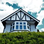 Tudor-style house facade with a bay window against a vibrant sky and greenery. — "Affordable and Reliable Window Replacement