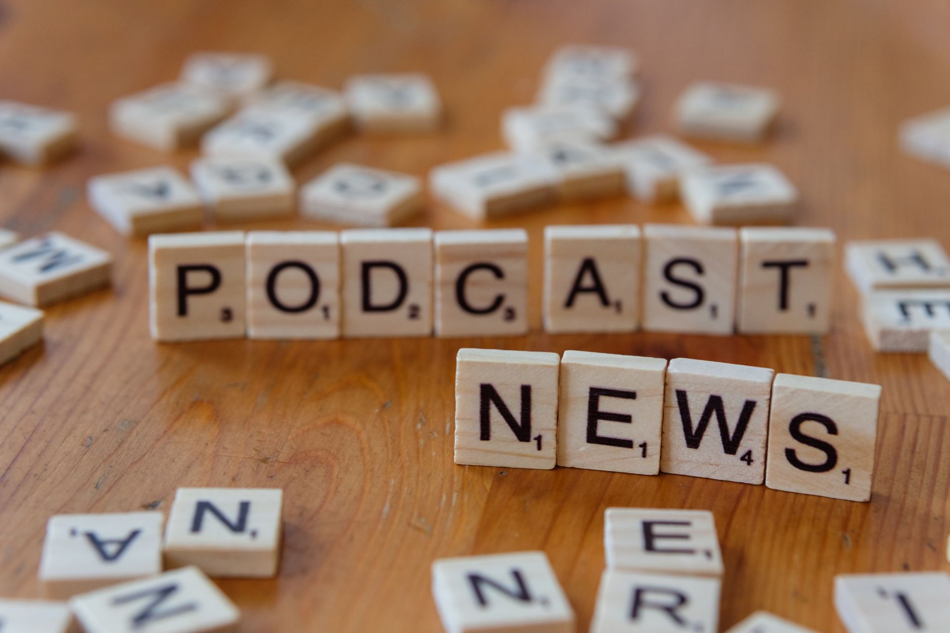 Wooden letter tiles spelling out 'PODCAST NEWS' on a wooden surface. — Chaos Engineering in Serverless: Building Resilient Sy