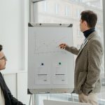 Two professionals examining graphs during an office presentation. — Dr. Andrew Gomes: Pioneering Advanced Neuroimaging in Tra