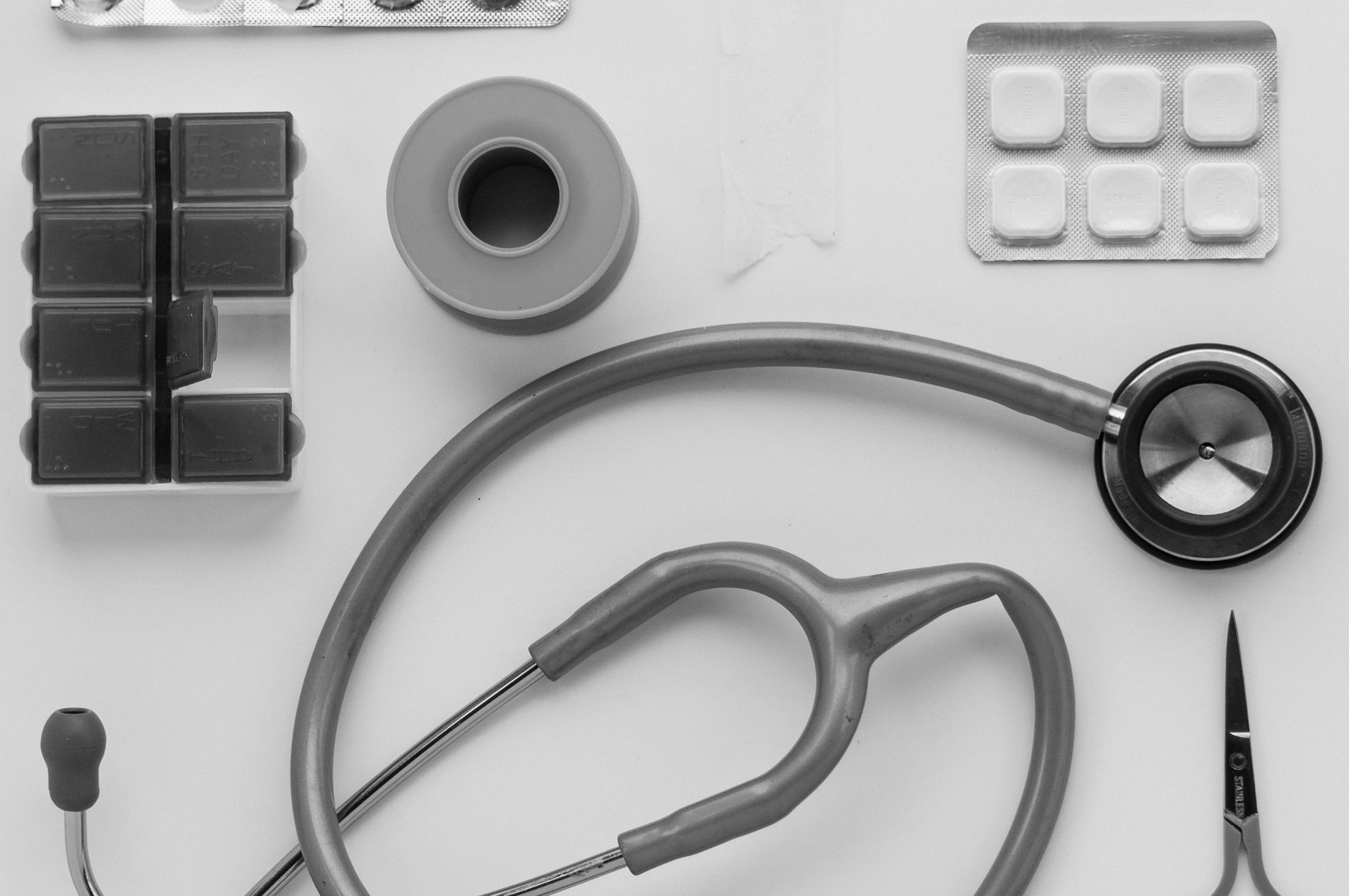 Top view of medical instruments and pills arranged on a white background. — Dr. Edward Lubin: Minimizing Medication While Max