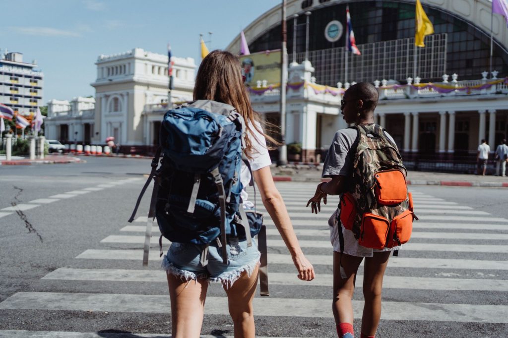 Two travelers with backpacks cross a city street near a historic building, symbolizing adventure and travel. — "Efficient Tra
