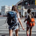 Two travelers with backpacks cross a city street near a historic building, symbolizing adventure and travel. — "Efficient Tra