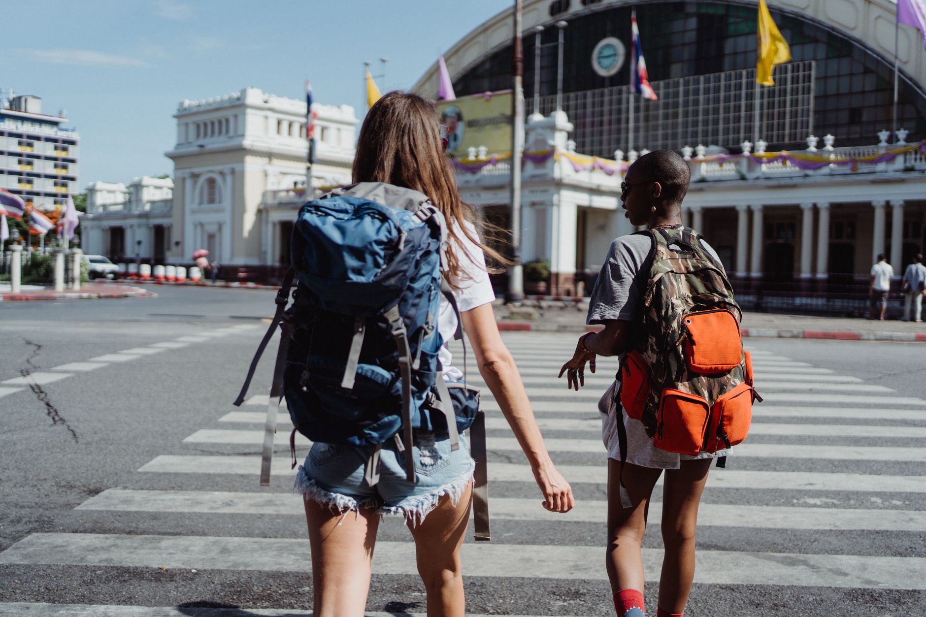 Two travelers with backpacks cross a city street near a historic building, symbolizing adventure and travel. — "Efficient Tra