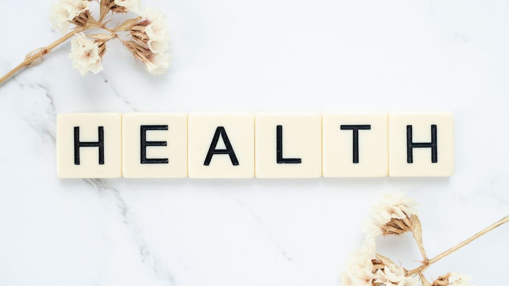 Creative arrangement of scrabble tiles spelling 'Health' with white flowers on a marble surface. — Exploring Prescription Dru