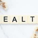 Creative arrangement of scrabble tiles spelling 'Health' with white flowers on a marble surface. — Exploring Prescription Dru