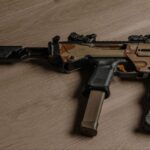 A close-up view of a tactical firearm with an adjustable brace setup on a wooden surface.