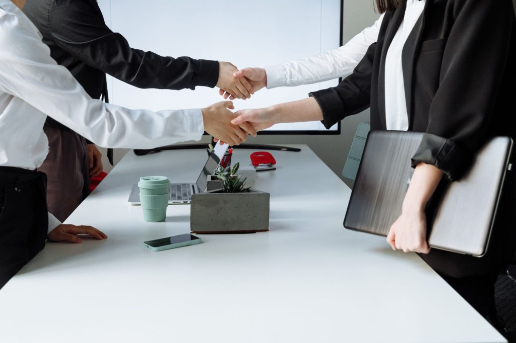 Professionals sealing a deal with a handshake across a conference table during a business meeting. — Momentum Advisors: Empow