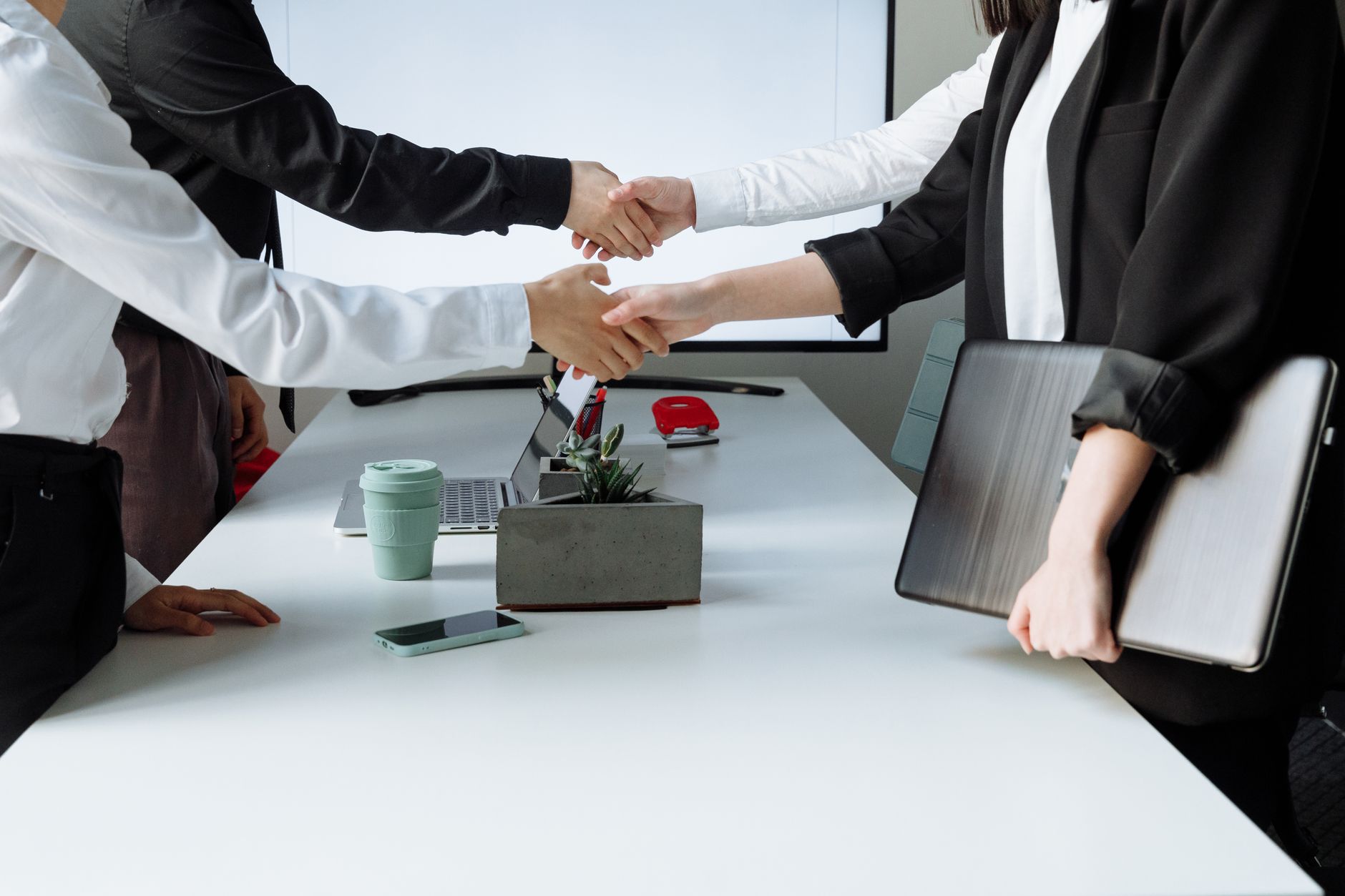 Professionals sealing a deal with a handshake across a conference table during a business meeting. — Momentum Advisors: Empow