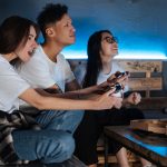 Three friends play video games together indoors, enjoying pizza and fun times. — MPO700 Slot Login Portal Designed for Easy N