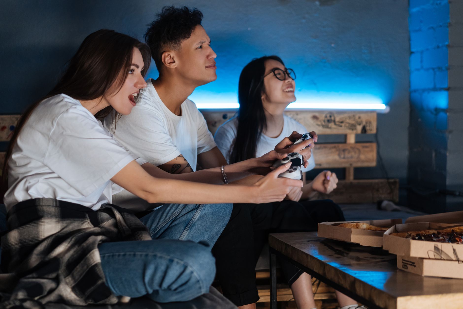 Three friends play video games together indoors, enjoying pizza and fun times. — MPO700 Slot Login Portal Designed for Easy N