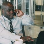 Professional man multitasking, talking on the phone while using a laptop in an office. — Navigating Hypertension Waters: Dr.M