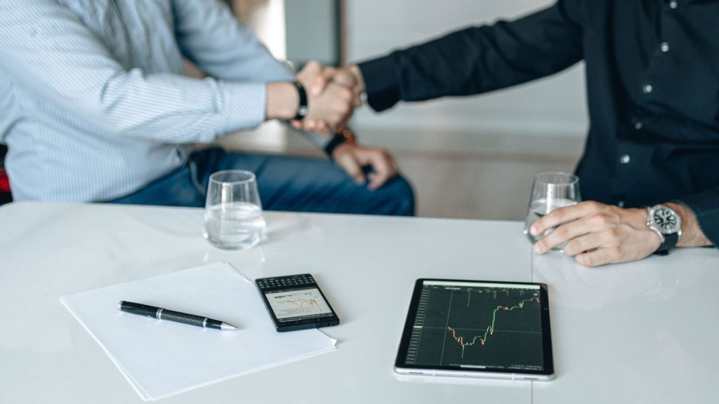 Business meeting with handshake and financial analysis displayed on a tablet. — Payday Loans Quebec Borrowers Can Get With Le