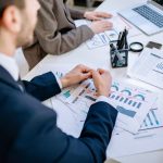 Business team analyzing financial graphs at a meeting table, fostering collaboration in an office environment. — Rose Sarfo: