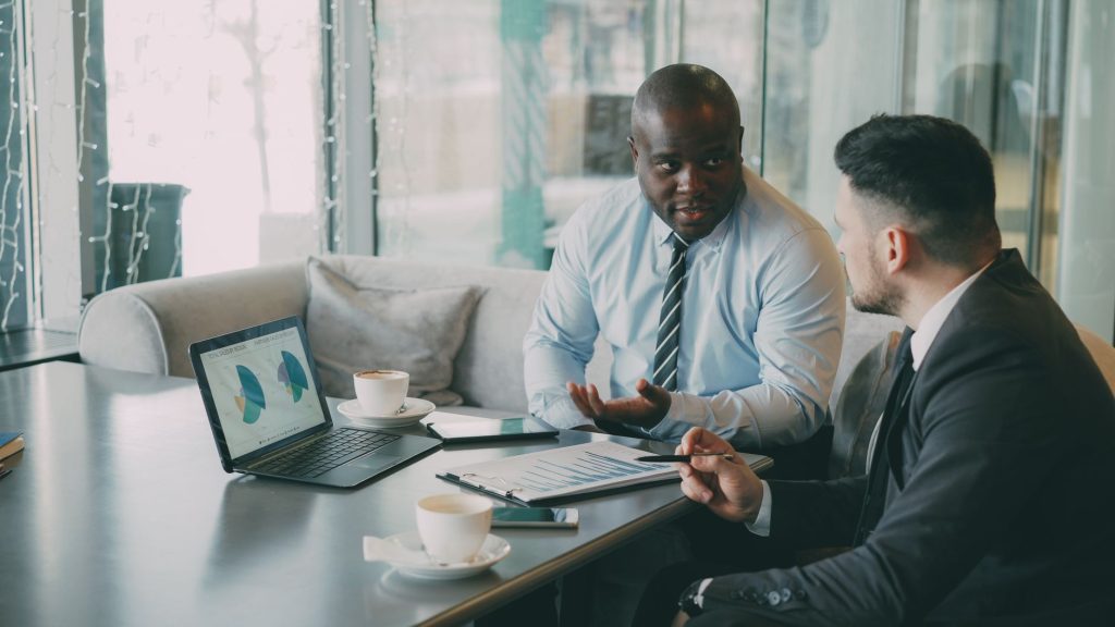 Two business professionals engaged in discussion over laptops and documents. — Sex Products for Confidence and Intimacy: A Gu