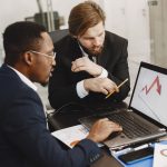 Two business professionals discuss marketing data on a laptop in a modern office. — Sports Broadcast Provides Stable, Buffer-