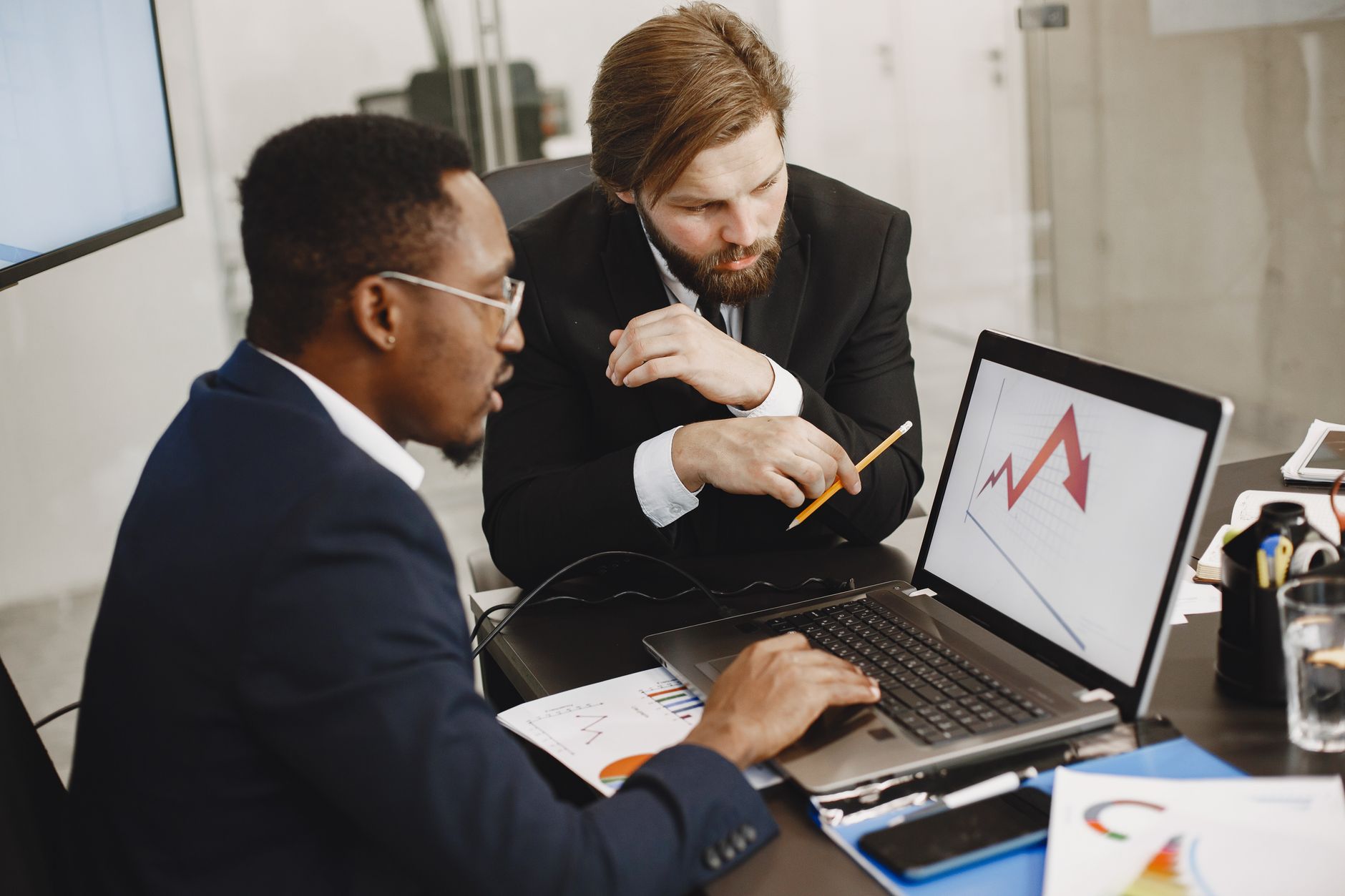 Two business professionals discuss marketing data on a laptop in a modern office. — Sports Broadcast Provides Stable, Buffer-