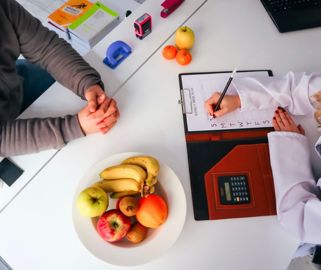 Top view of a dietitian planning a healthy diet with fresh fruits on the table, focusing on health and nutrition. — The Dr He