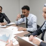 A multicultural team engaged in discussion during an office meeting, highlighting diversity and teamwork. — Travertine Pavers