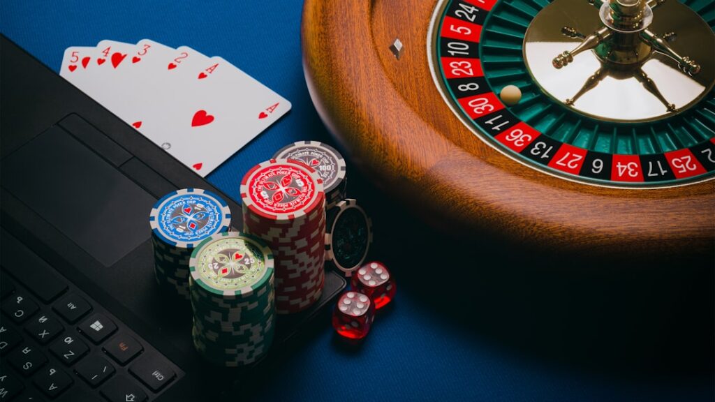A close-up of poker chips, playing cards, and a roulette wheel on a blue background.