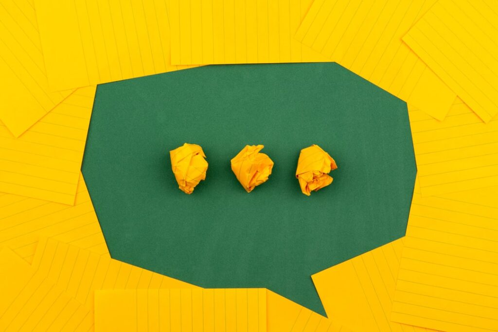 Crumpled yellow paper balls on a green background surrounded by lined paper, symbolizing chaotic thoughts.
