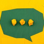 Crumpled yellow paper balls on a green background surrounded by lined paper, symbolizing chaotic thoughts.