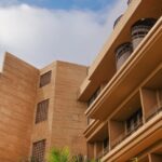 Modern architectural building exterior with balconies and windows under a cloudy sky