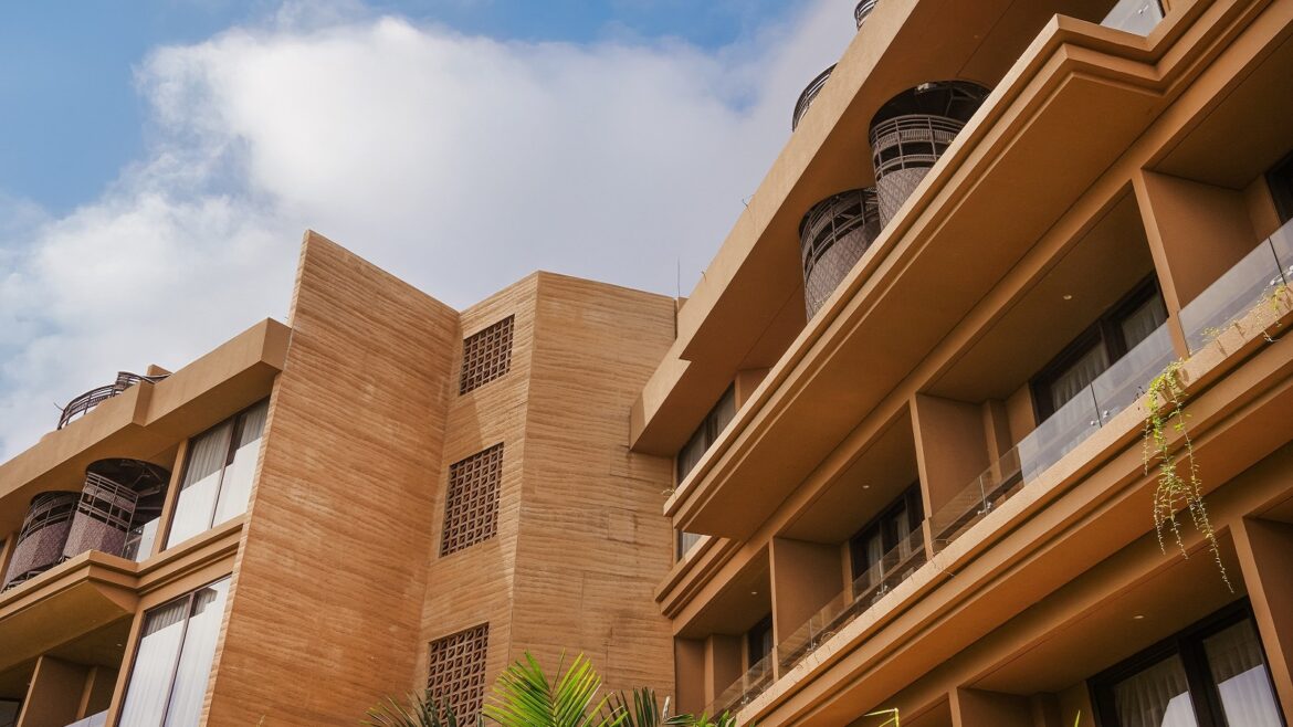 Modern architectural building exterior with balconies and windows under a cloudy sky